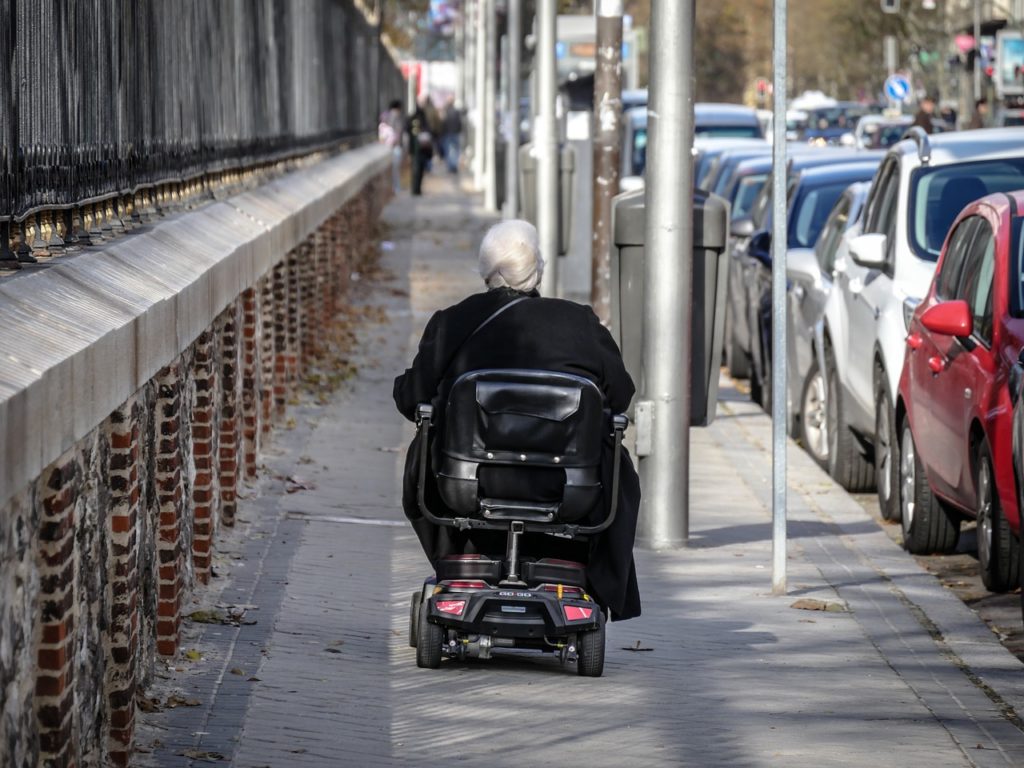 ältere Frau, die im Rollstuhl spazieren geht